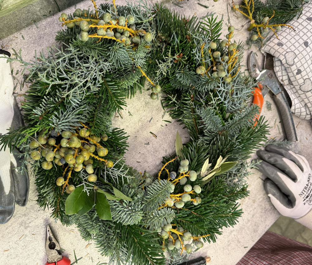 Ein handgefertigter grüner Kranz von einer Teilnehmerin an unserem Kranzbinden Workshop in Bozen gebunden.